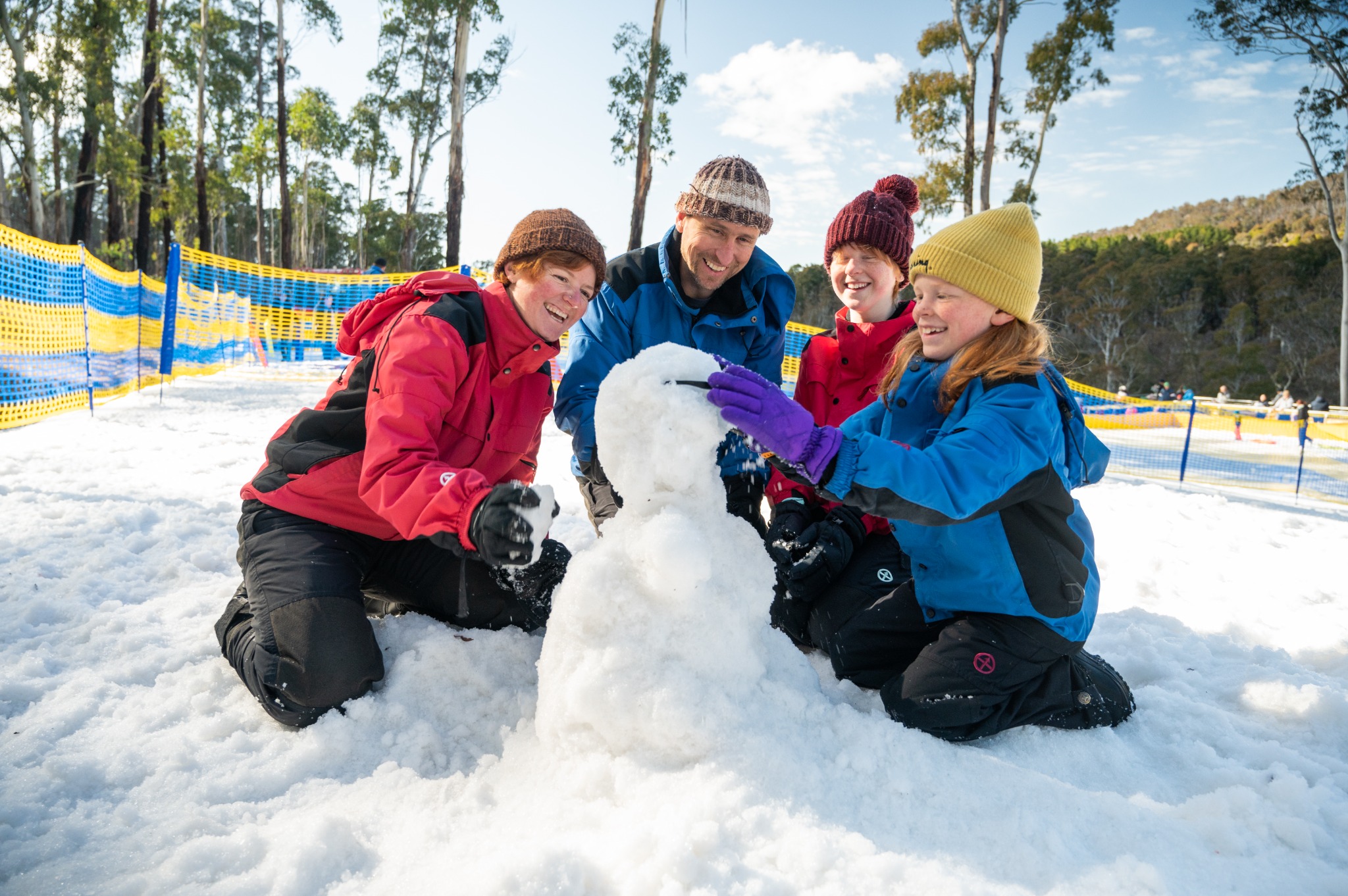 A family enjoying snowplay and building a snowman in made snow